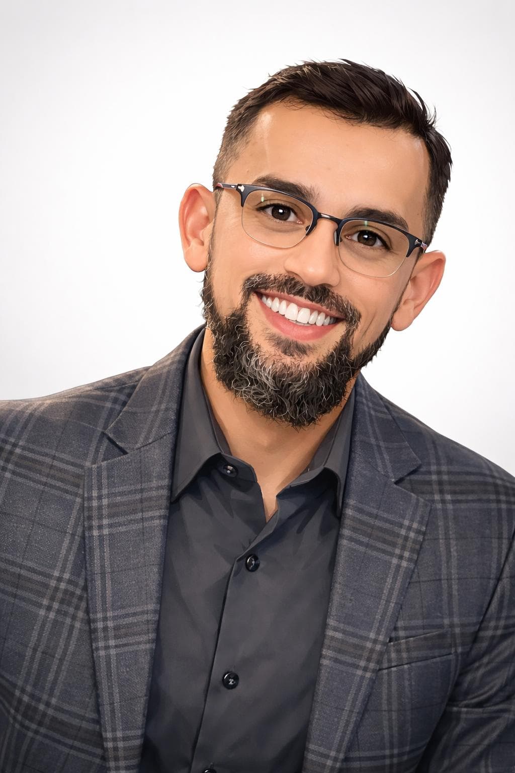 Smiling man with glasses and a beard wearing a grey plaid blazer and shirt.